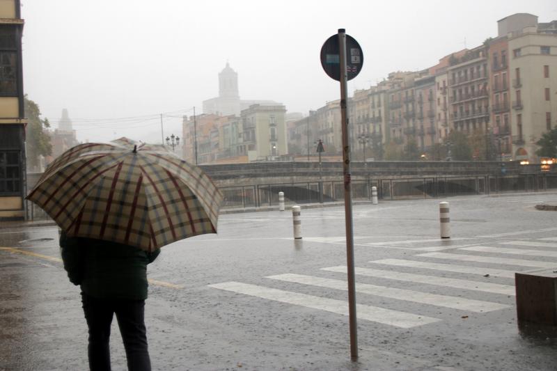 A man walks with an umbrella in a rainy Girona