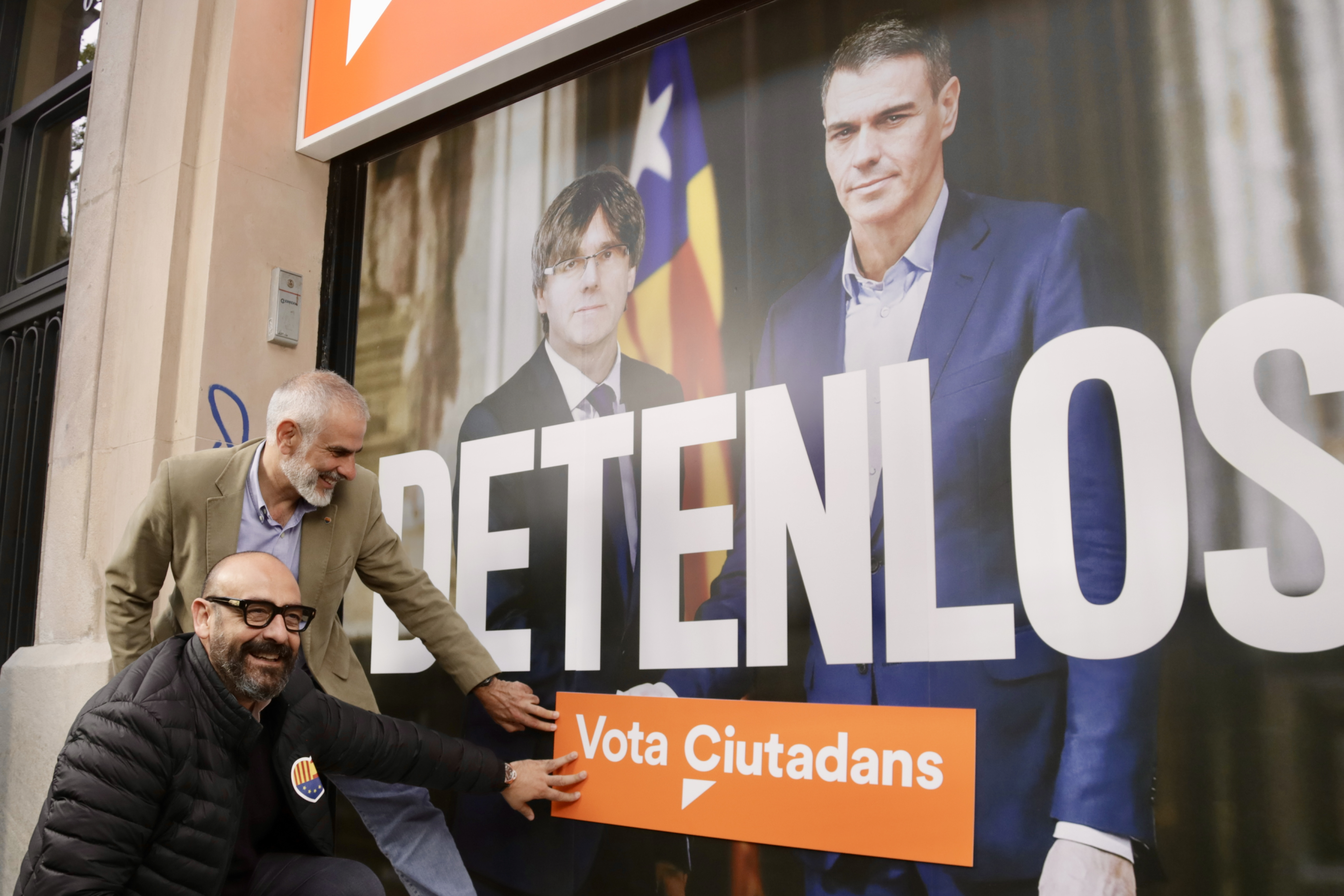El candidat de Cs, Carlos Carrizosa, amb Jordi Cañas, posen una enganxina demanant el vot a la seu del partit, tematitzada amb la imatge del cartell electoral
