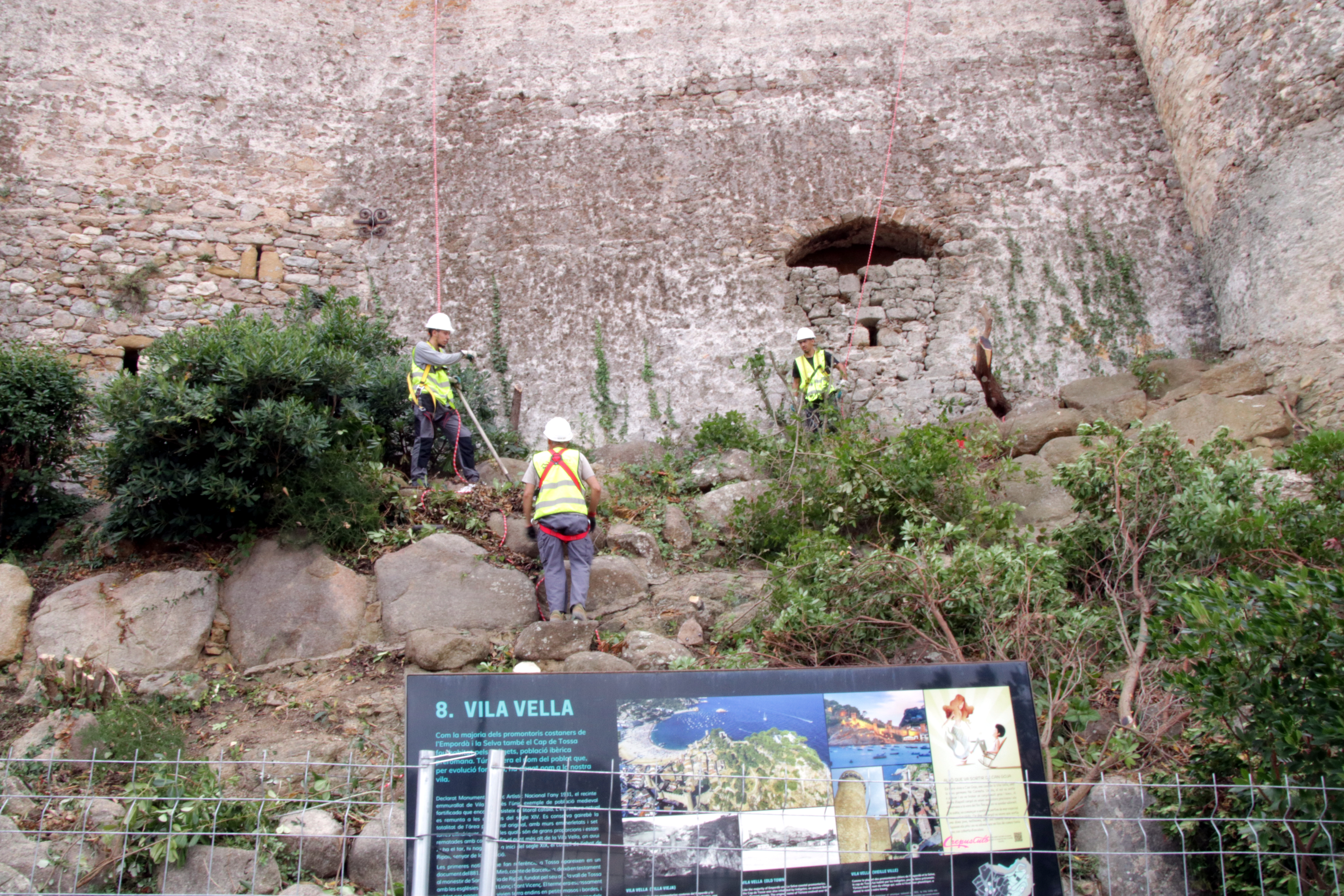 Three workers carrying out work at the walled enclosure of Tossa de Mar.