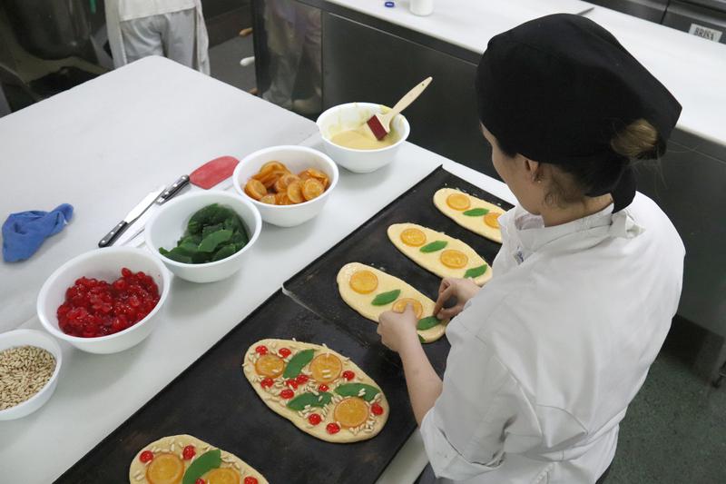 A pastry chef prepares Sant Joan coques with candied fruit and pine nuts