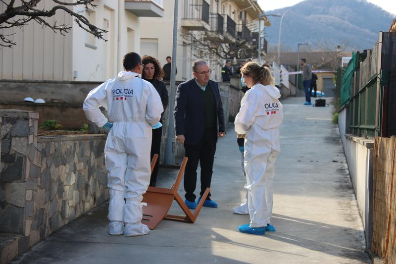 Police officers stand outside the house in Sant Joan less Fonts alongside a prosecutor and lawyer