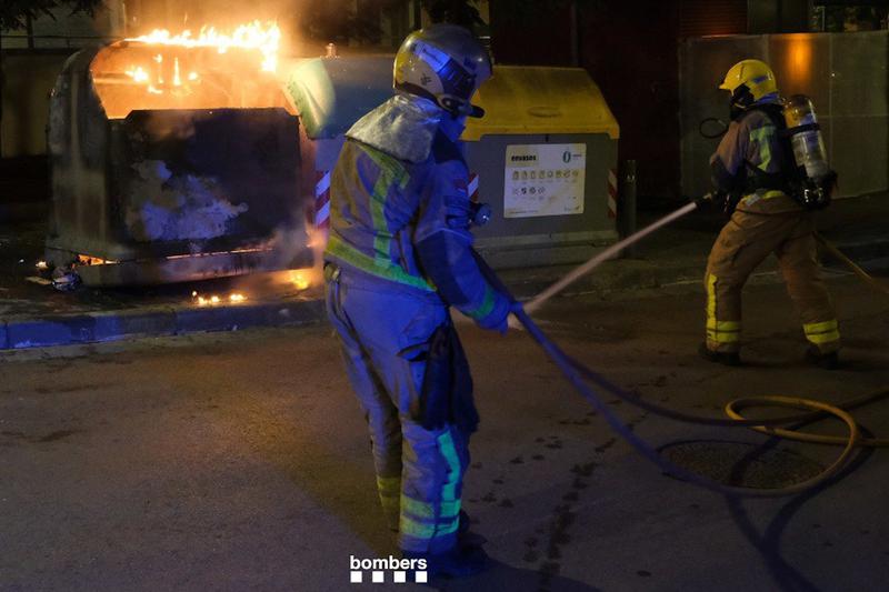 A trash can on fire with firefighters working to extinguish the flames in an archive picture