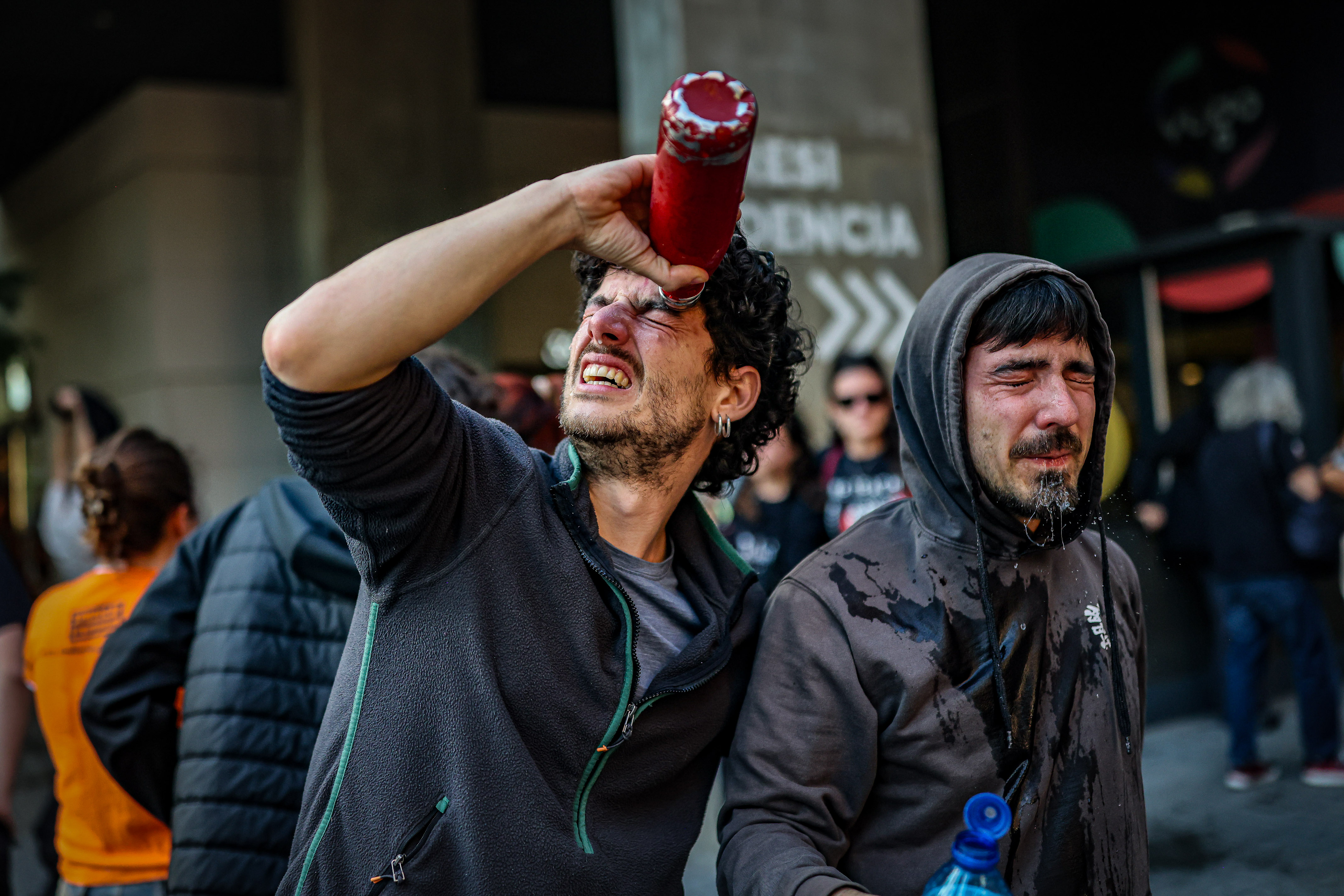Un manifestant es posa aigua a l'ull després que els Mossos hagin ruixat els manifestants amb gas pebre