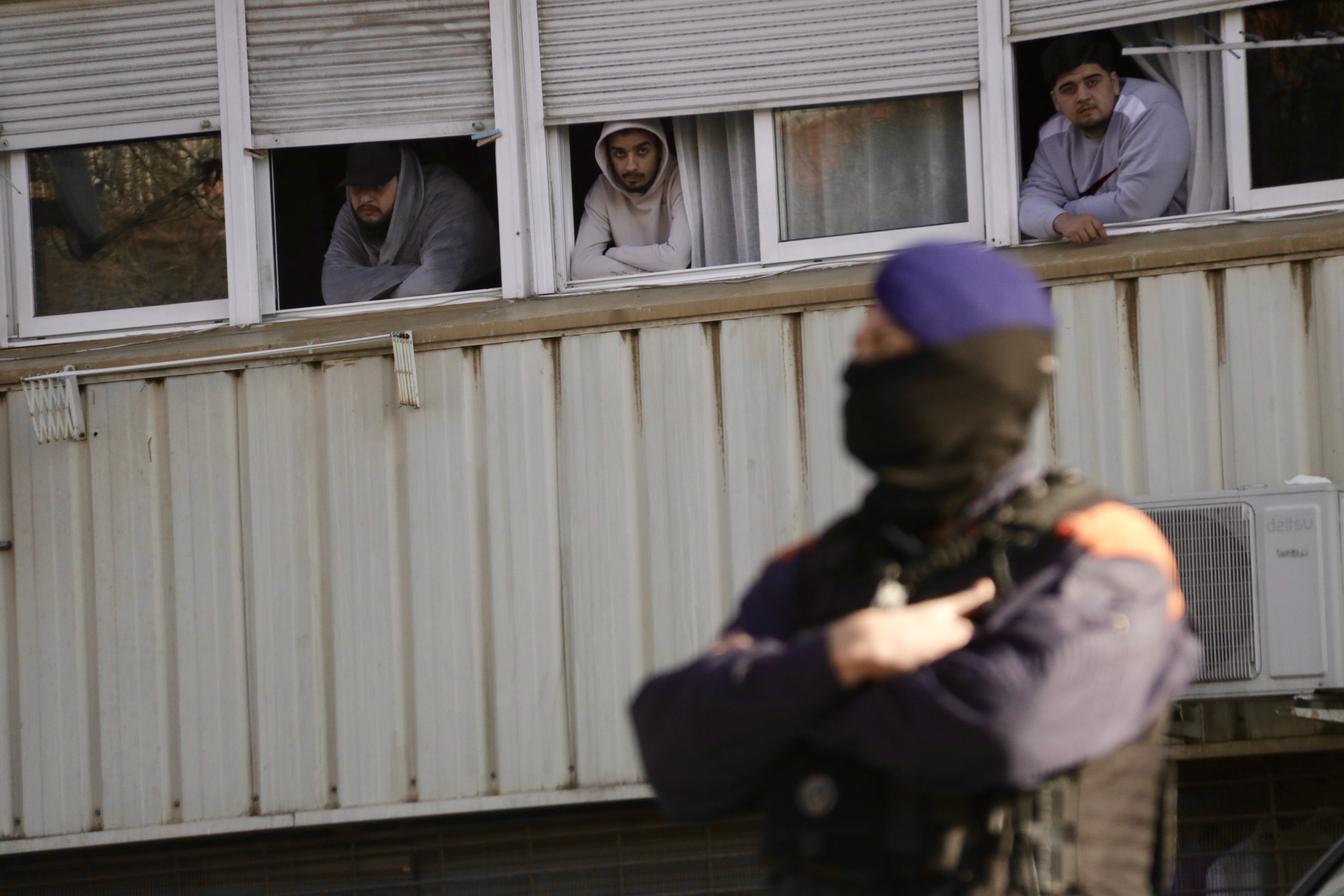 People looking out apartment windows at the police operation on the street