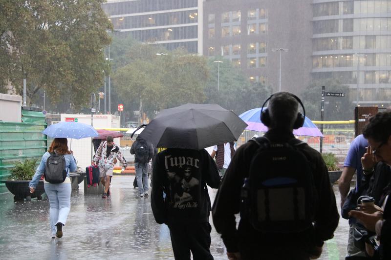Train passengers leaving Sants station during rain in Barcelona.