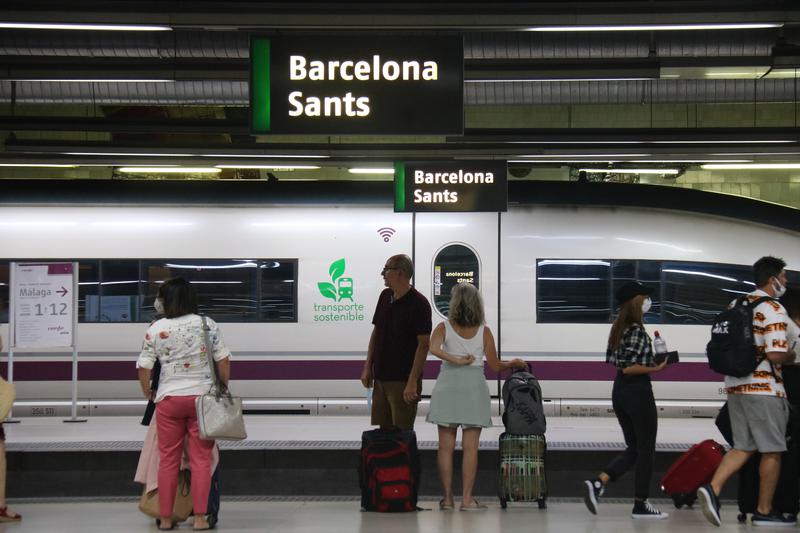 Several high-speed train passengers at Barcelona Sants train station with a Renfe AVE train on the background
