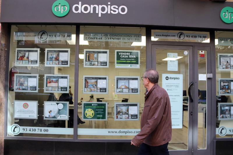 A man walks past signs advertising apartments for sale at the “donpiso” real estate agency.