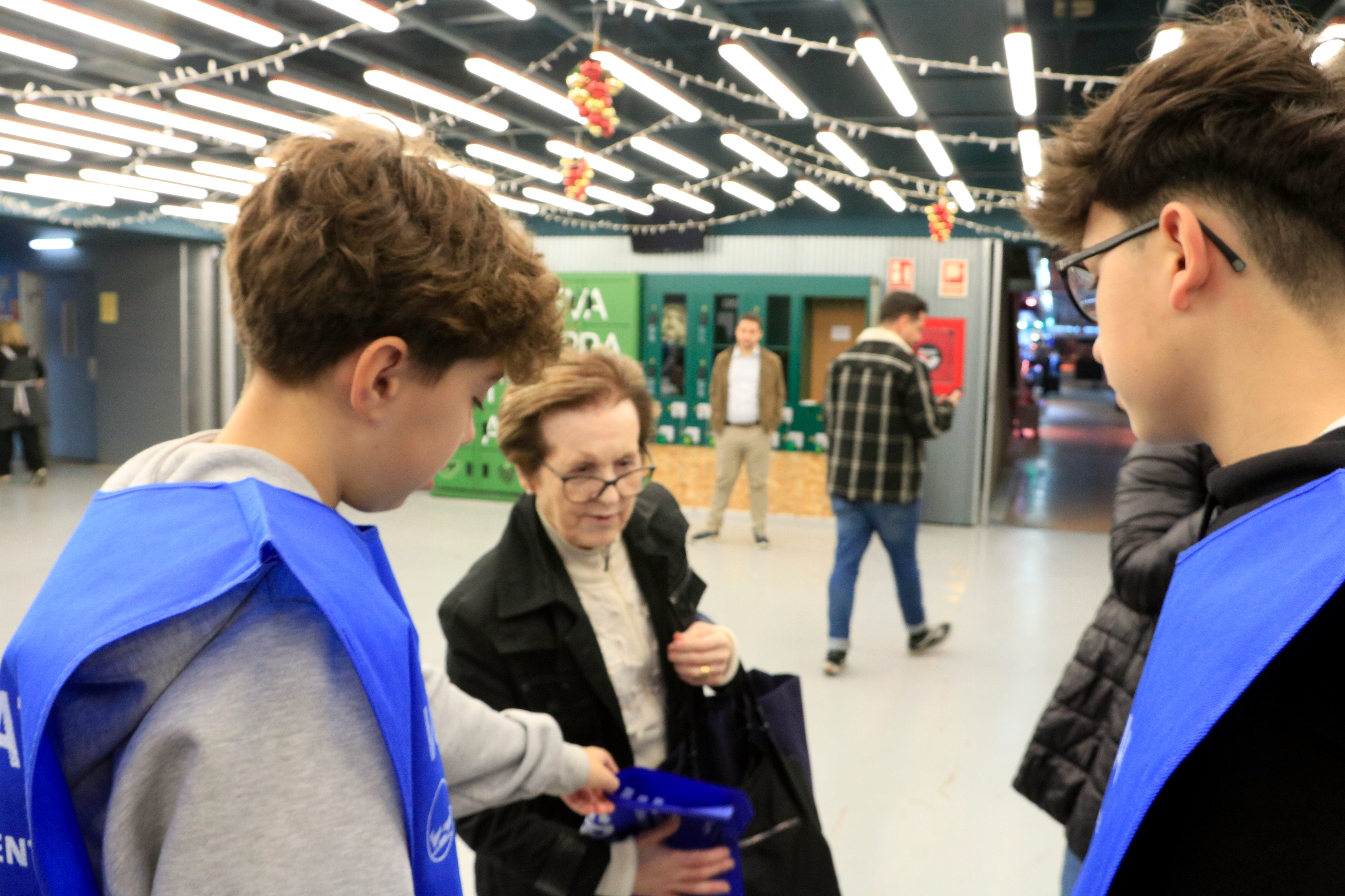 Volunteers hand a bag of Gran Recapte to a woman at the entrance of a supermarket on November 22