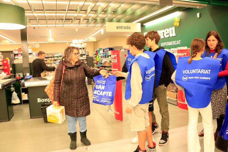 Volunteers hand a bag to a woman at the entrance of a supermarket