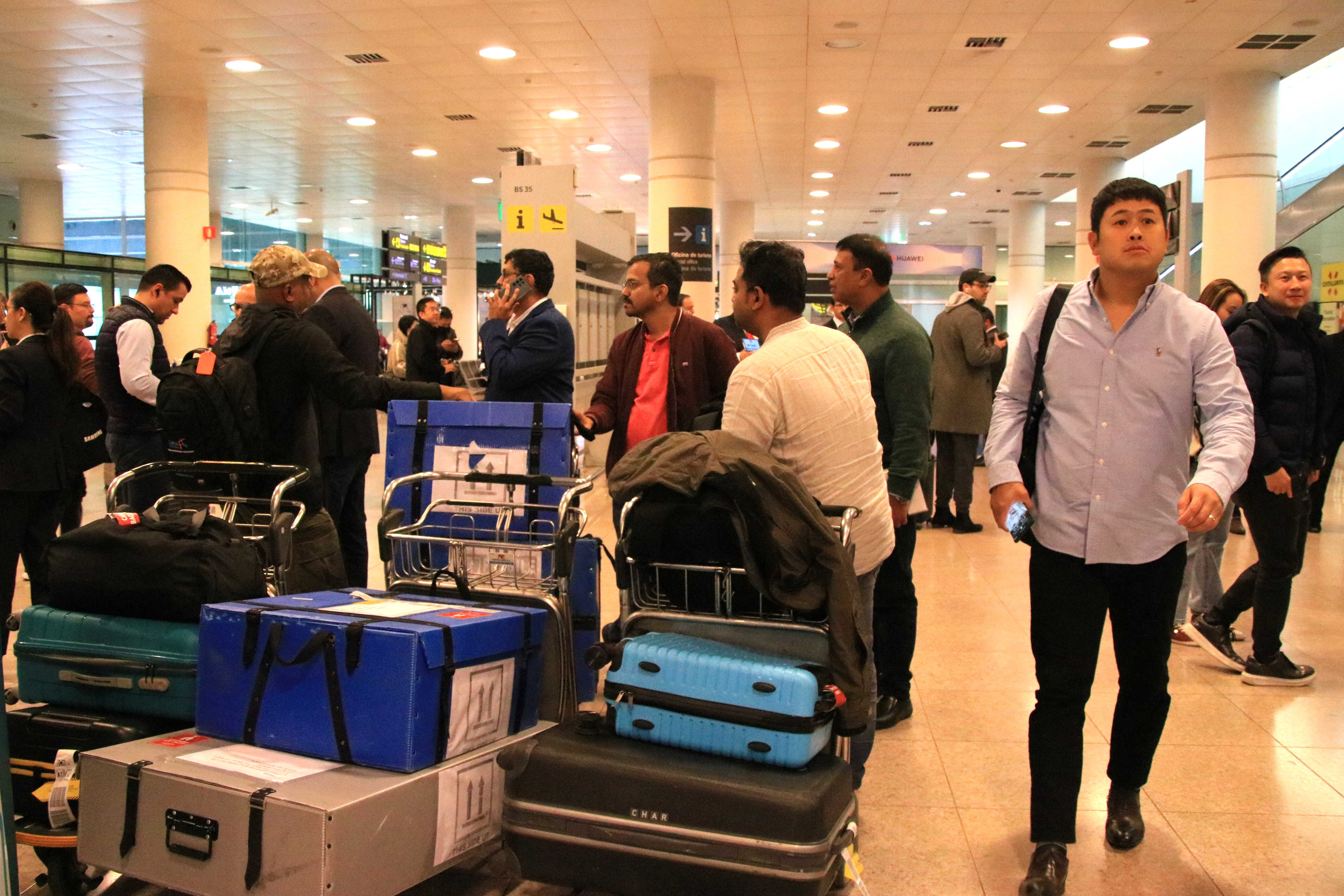 MWC visitors in Barcelona airport's terminal one with large suitcases and equipment on February 26, 2023