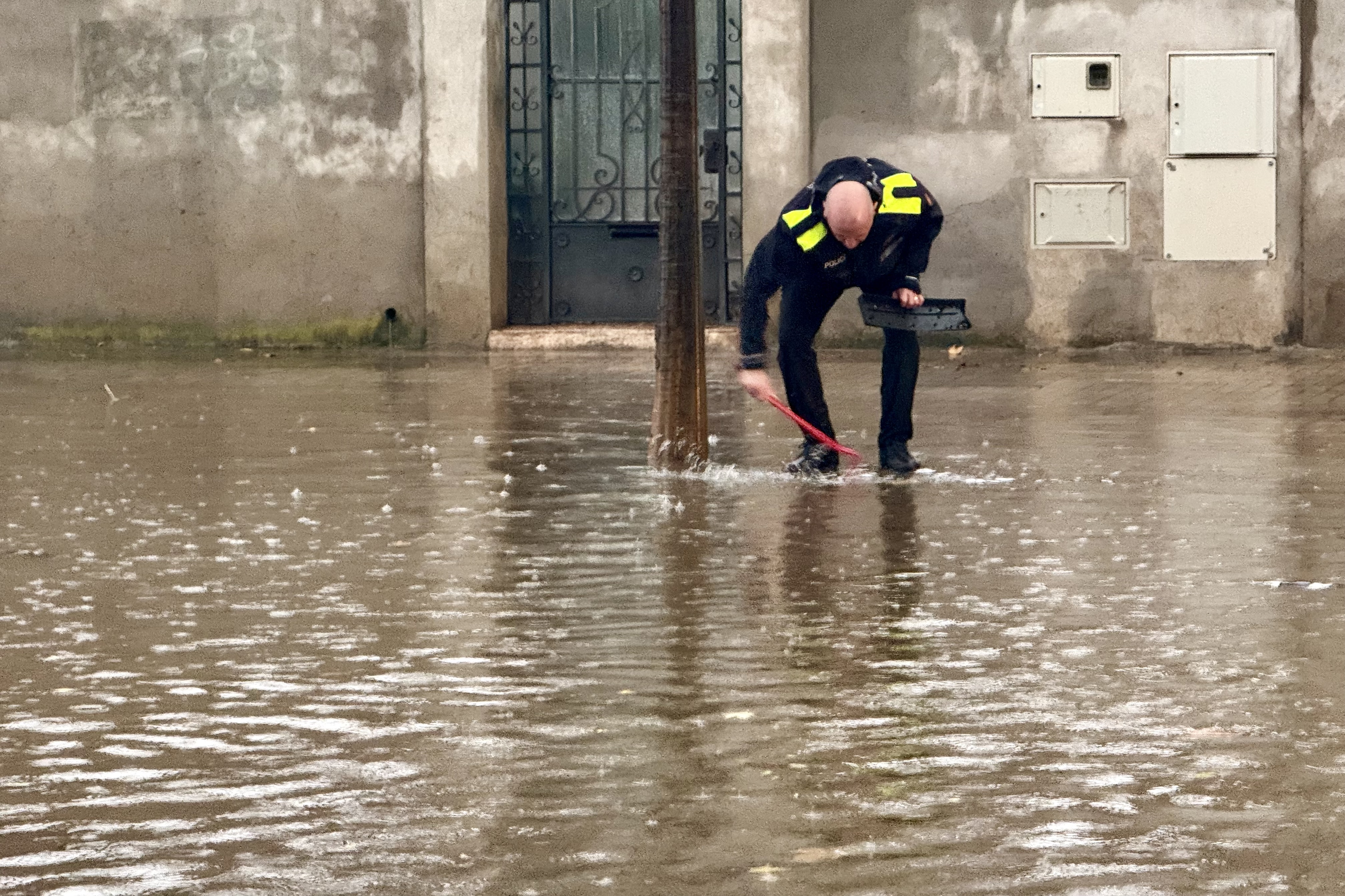 Un agent de la Plicia Municipal de Sabadell mira de destapar les entrades de les clavegueres a la rambla Ibèria de Sabadell.