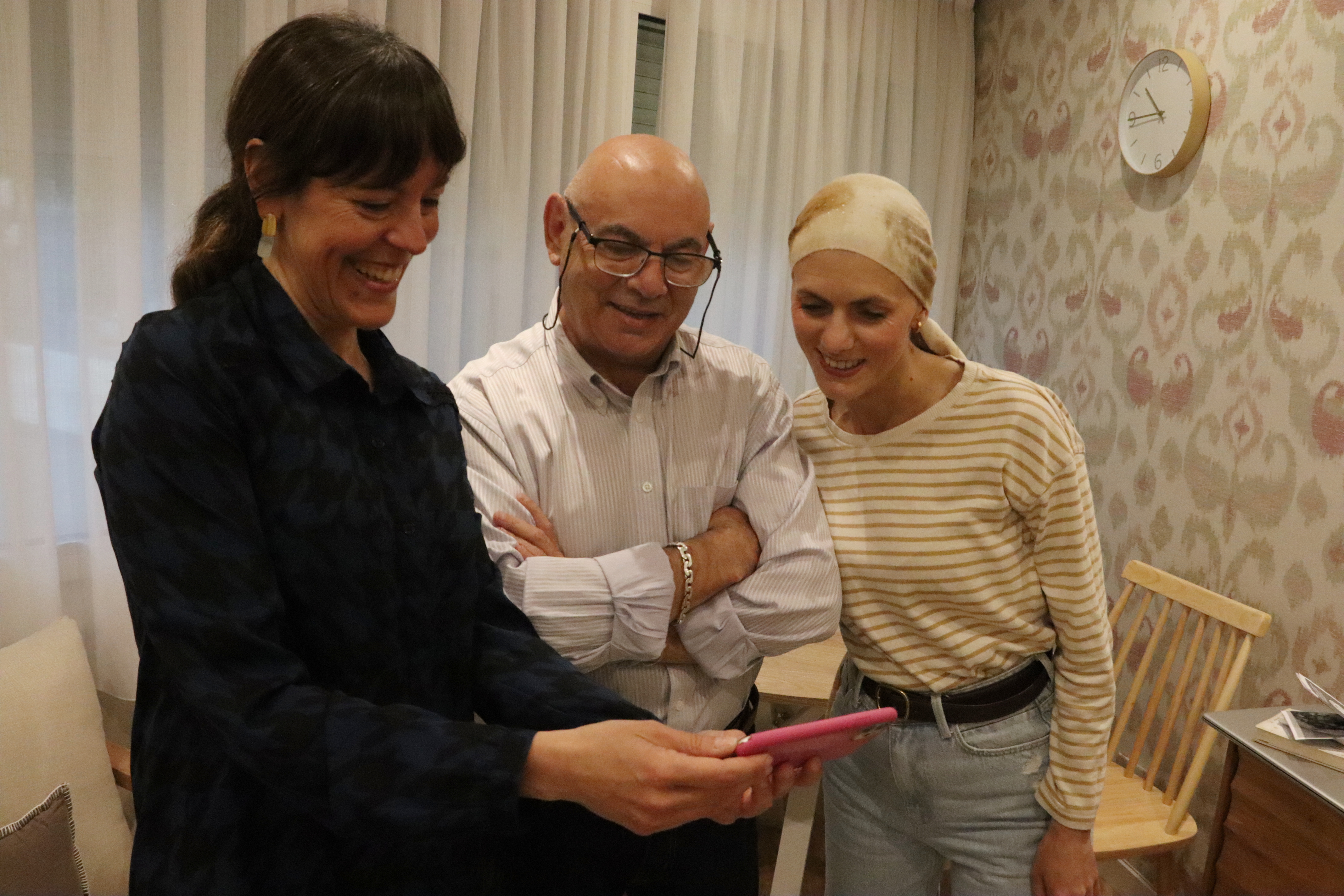 Cancer patient Beatriz Molina with her father and Marta Fernández from the Josep Carreras Foundation in Barcelona checking their phone