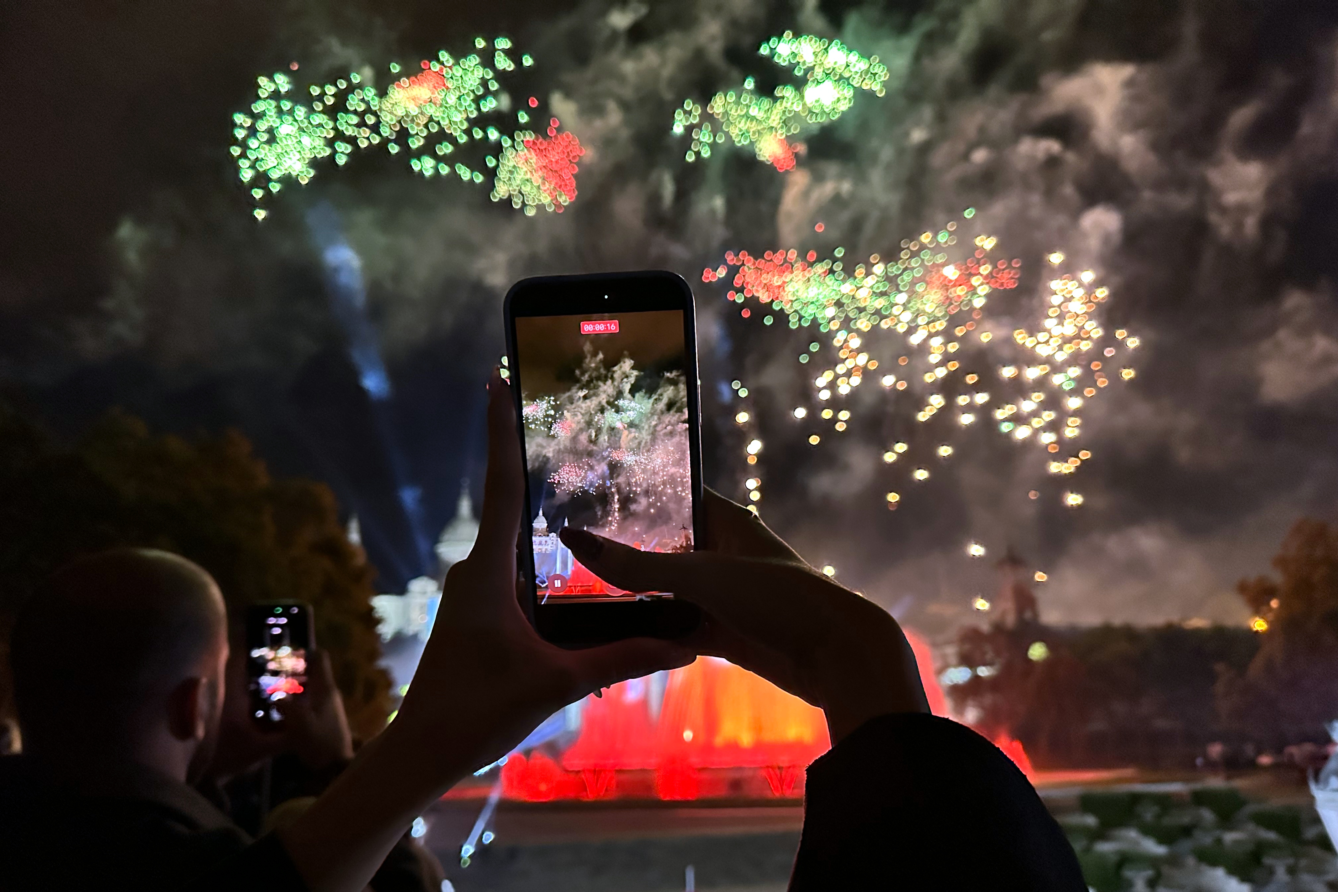 A spectator records the Piromusical closing La Mercè festivities on their phone