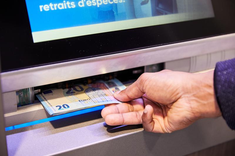 A person makes a cash withdrawal from an ATM