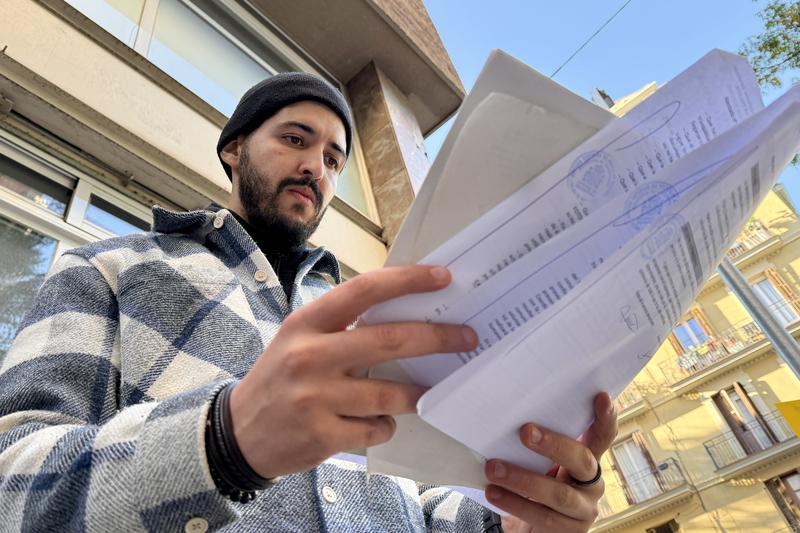 Amine M. looks at documents after giving his DNA sample in Barcelona