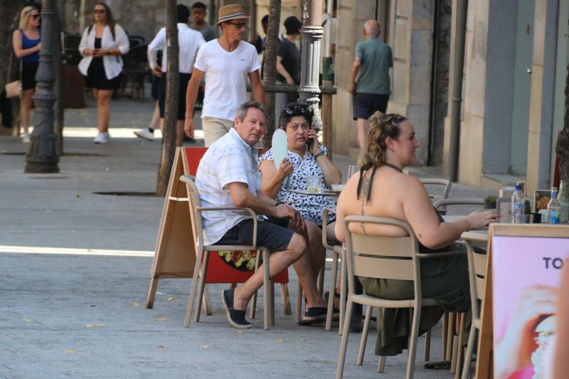 A customer at a bar terrace in Girona cools off with a fan