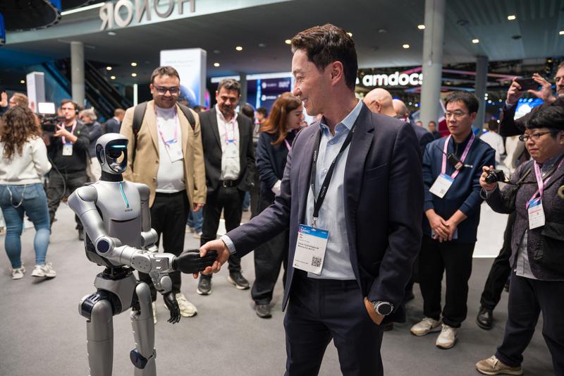 A congressman interacting with a robot at the Honor booth at MWC