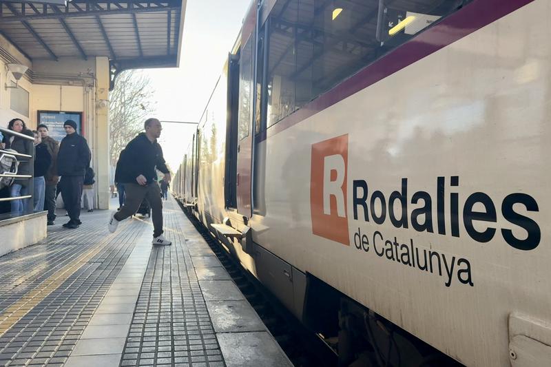 A commuter runs to catch a Rodalies commuter train