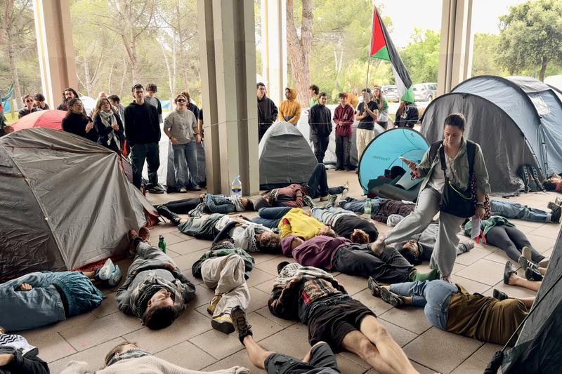 A woman walks through a group of students lying down to protest UAB's ties with Israel