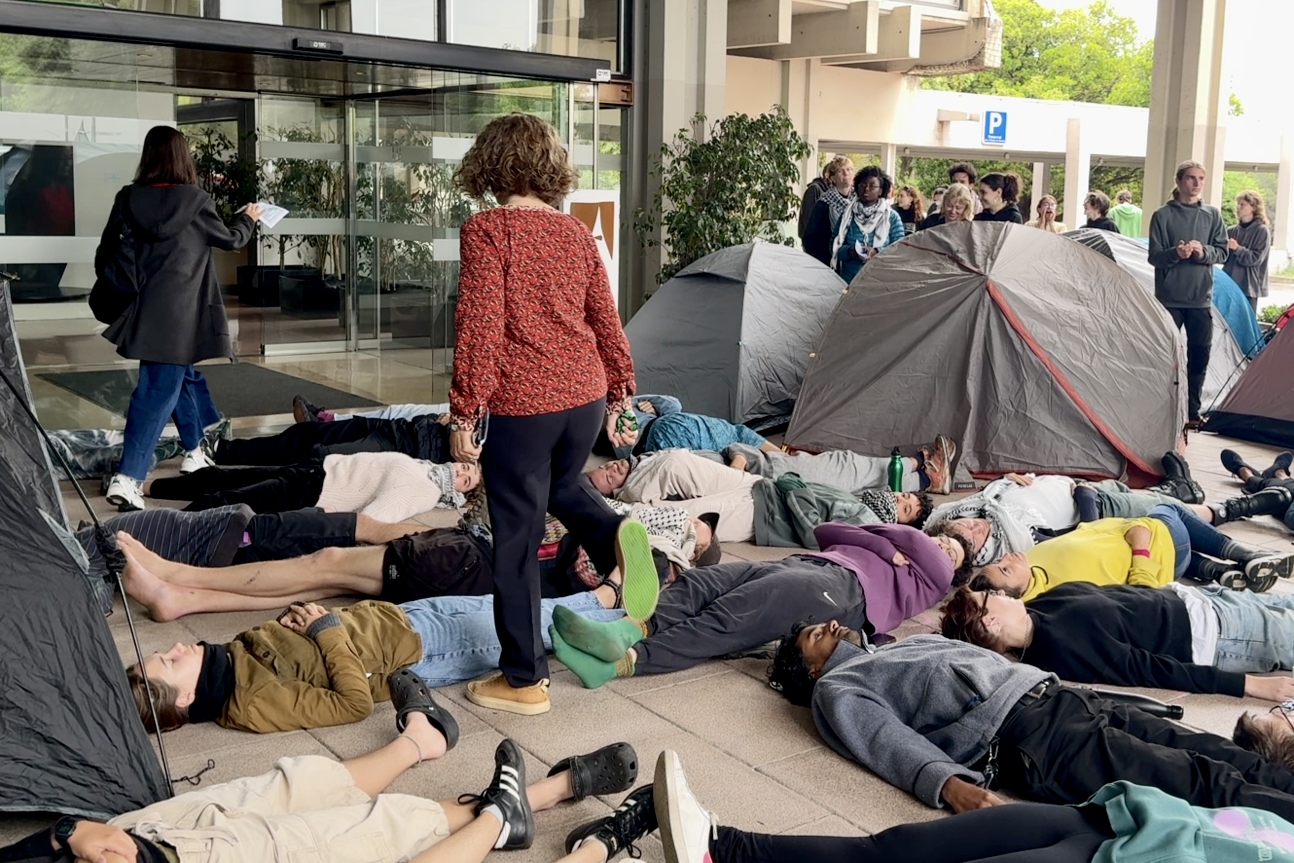Dues dones passen entre les persones estirades a terra en la protesta davant del Rectorat de la UAB.