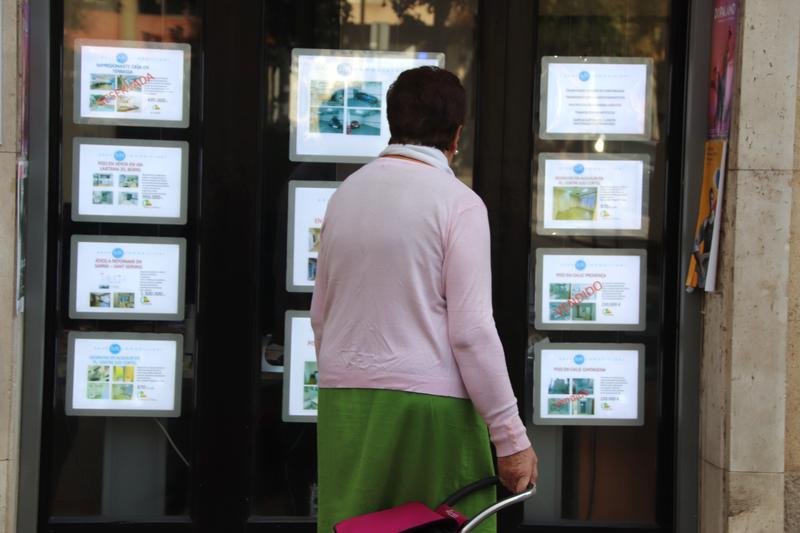 A woman examines homes for sale in an estate agent's window