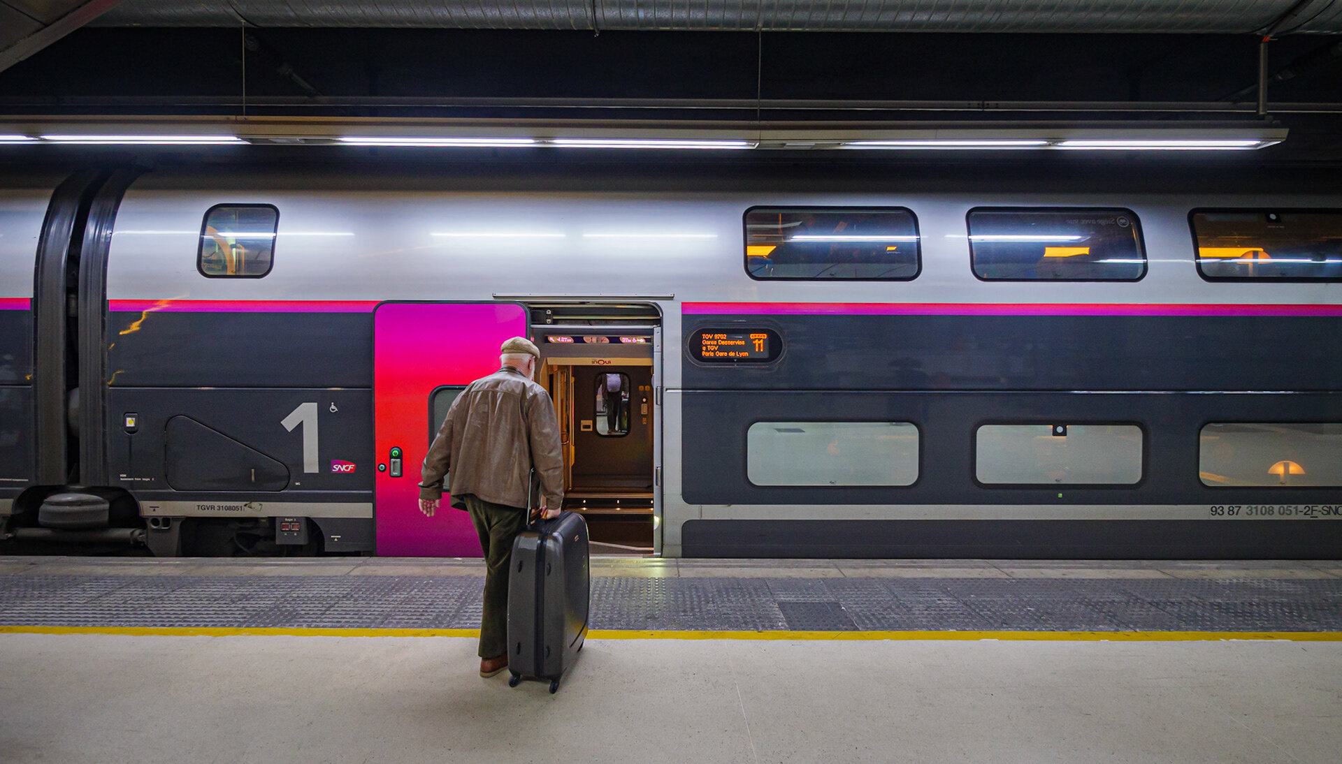 An SCNF high-speed train connecting Barcelona and Paris and a passenger carrying a suitcase