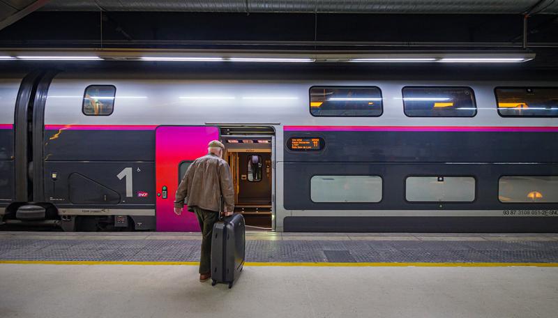 An SCNF high-speed train connecting Barcelona and Paris and a passenger carrying a suitcase 