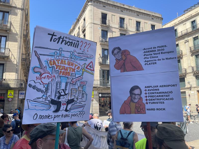 Two protest signs criticizing the economic model that activists say is too reliant on tourism