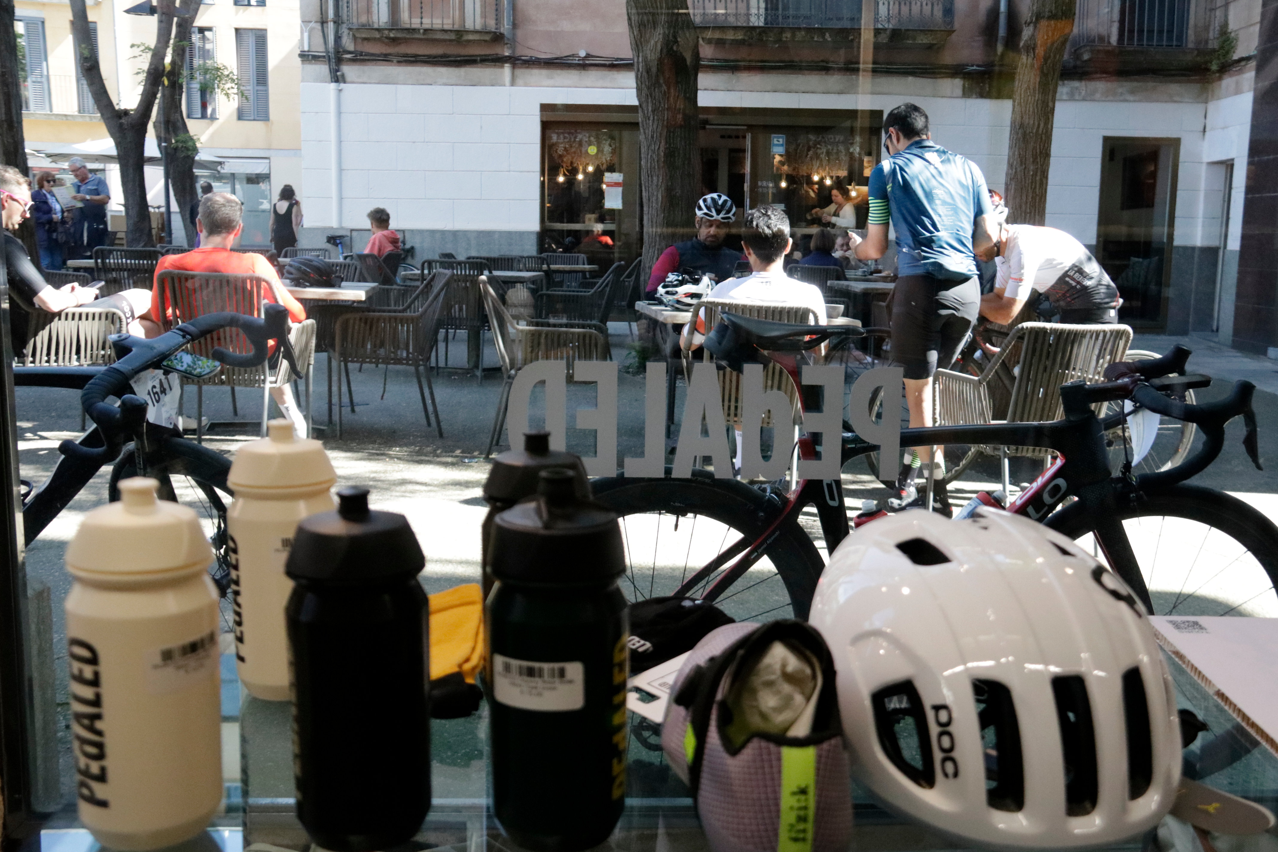 A helmet and water bottles on view in the window of Eat Sleep Cycle, in Girona