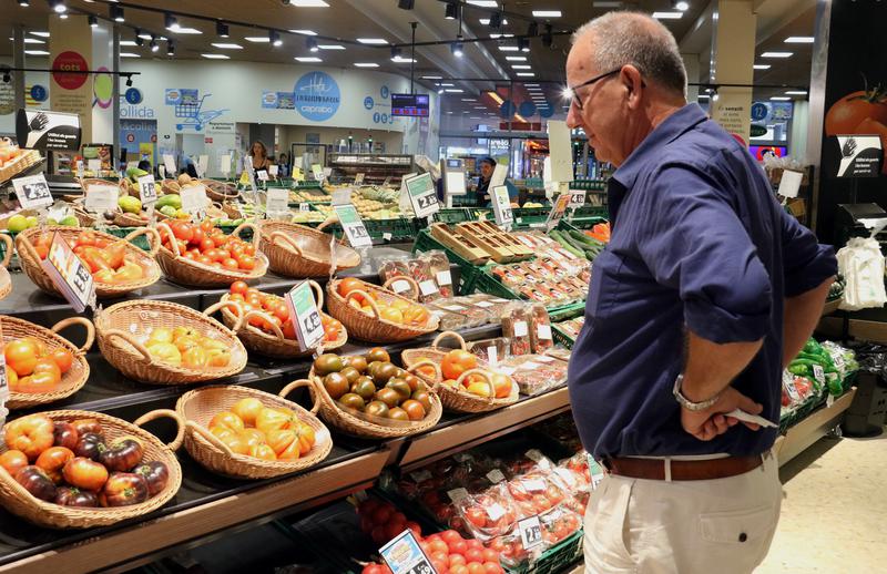 A customer eyes the price of fruit and vegetables in a Barcelona supermarket