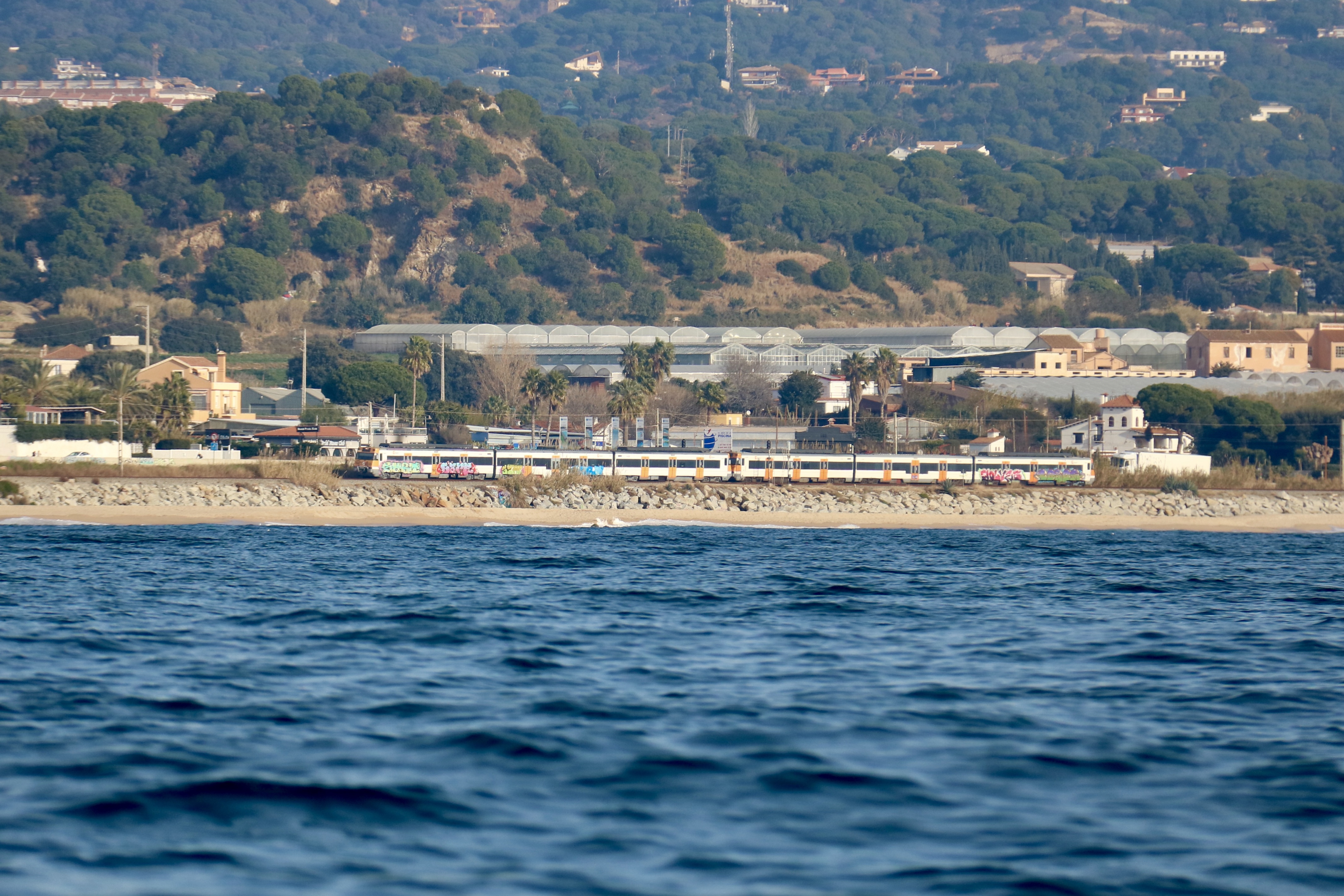 Un tren de Rodalies de la línia del Maresme a la costa de Mataró, vist des del mar.