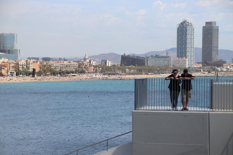 Two visitors view Barcelona from the viewpoint located in W Hotel in the Barceloneta, the city's skyline can be seen behind