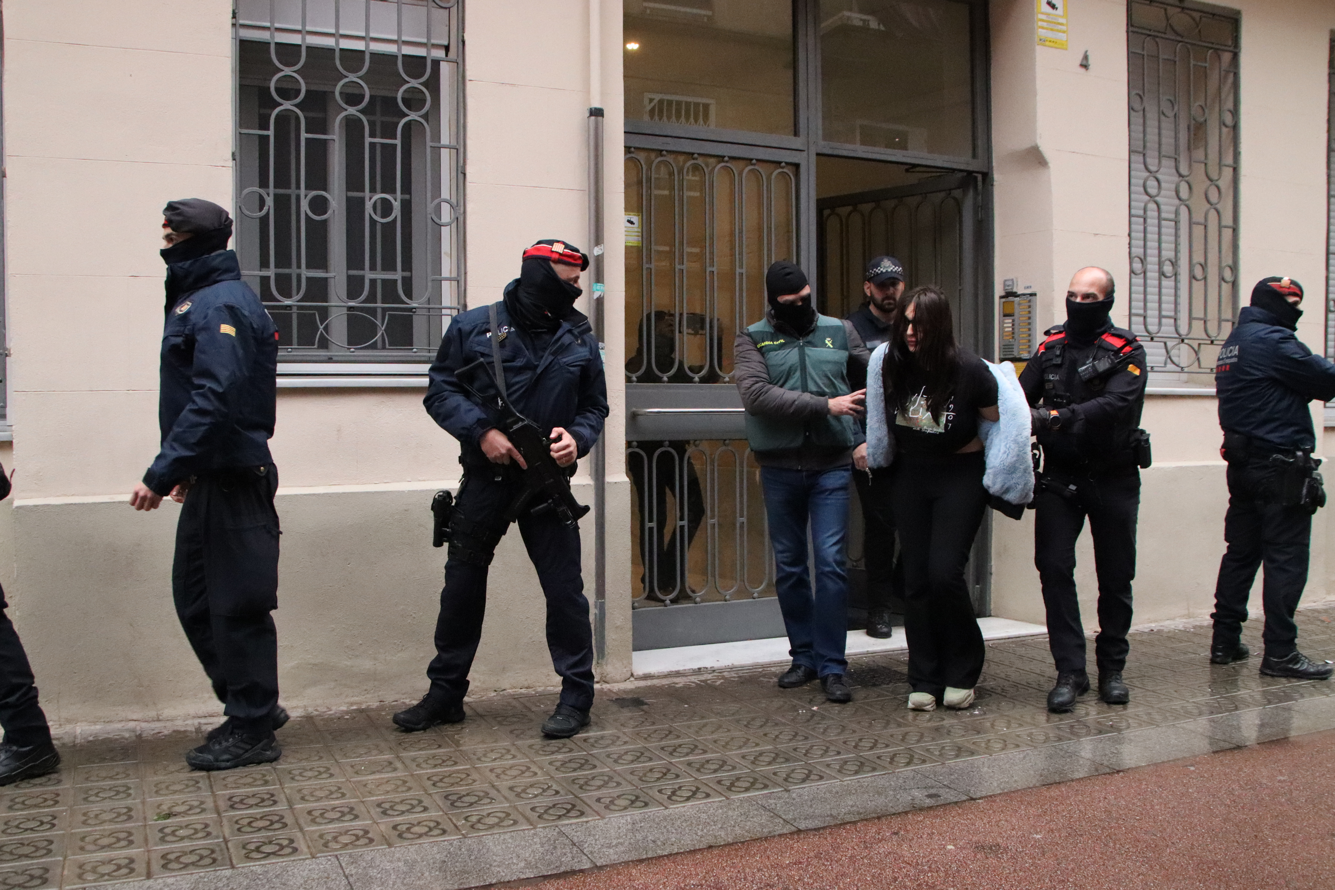 Mossos d'Esquadra and Guàrdia Civil police accompany an arrested woman outside an apartment in the neighborhood of Poblenou in Barcelona on December 11, 2024