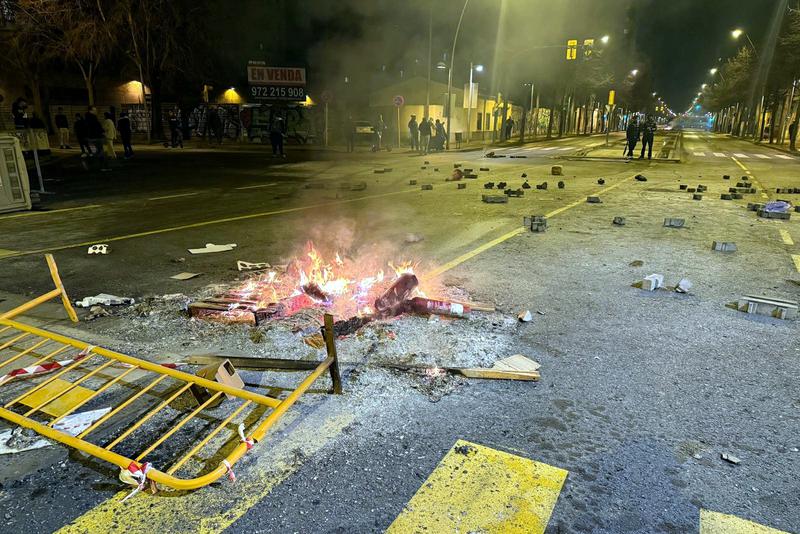 Passeig dels Països Catalans in Salt with stones on the road and the end of a street fire following the clashes