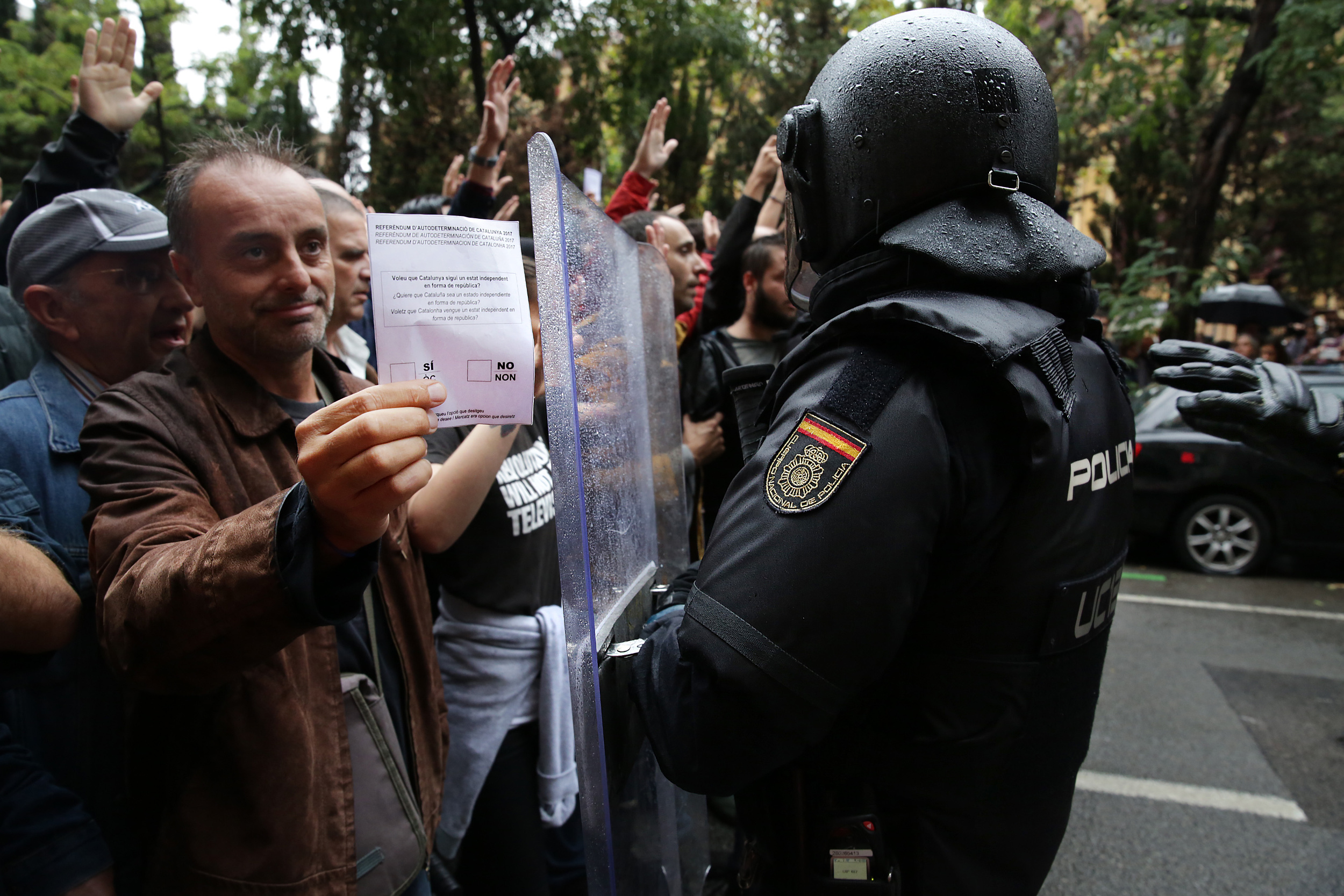 A demonstrator shows a ballot in front of a Spanish national police officer on October 1, 2017.