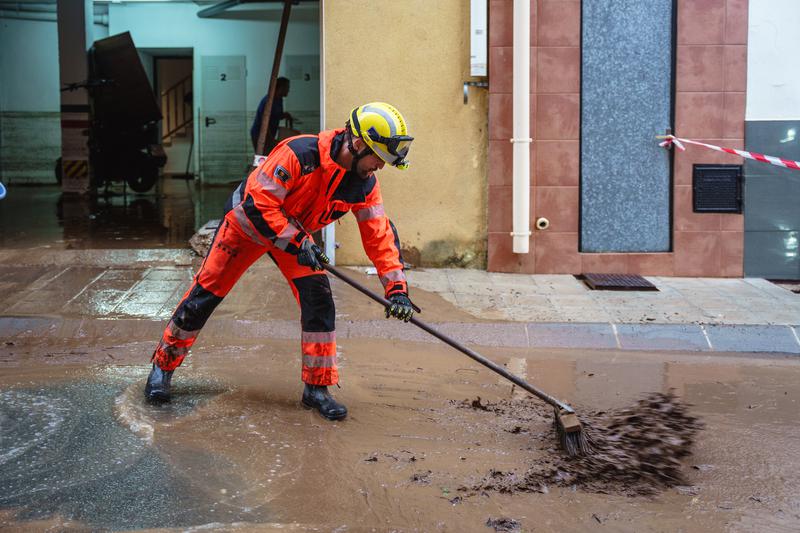 A firefighter clears water and mud from the road in Santa Bàrbara on October 13, 2025