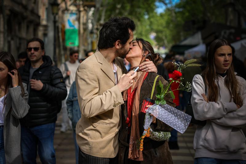 A couple kisses while she holds a rose on Sant Jordi 2024