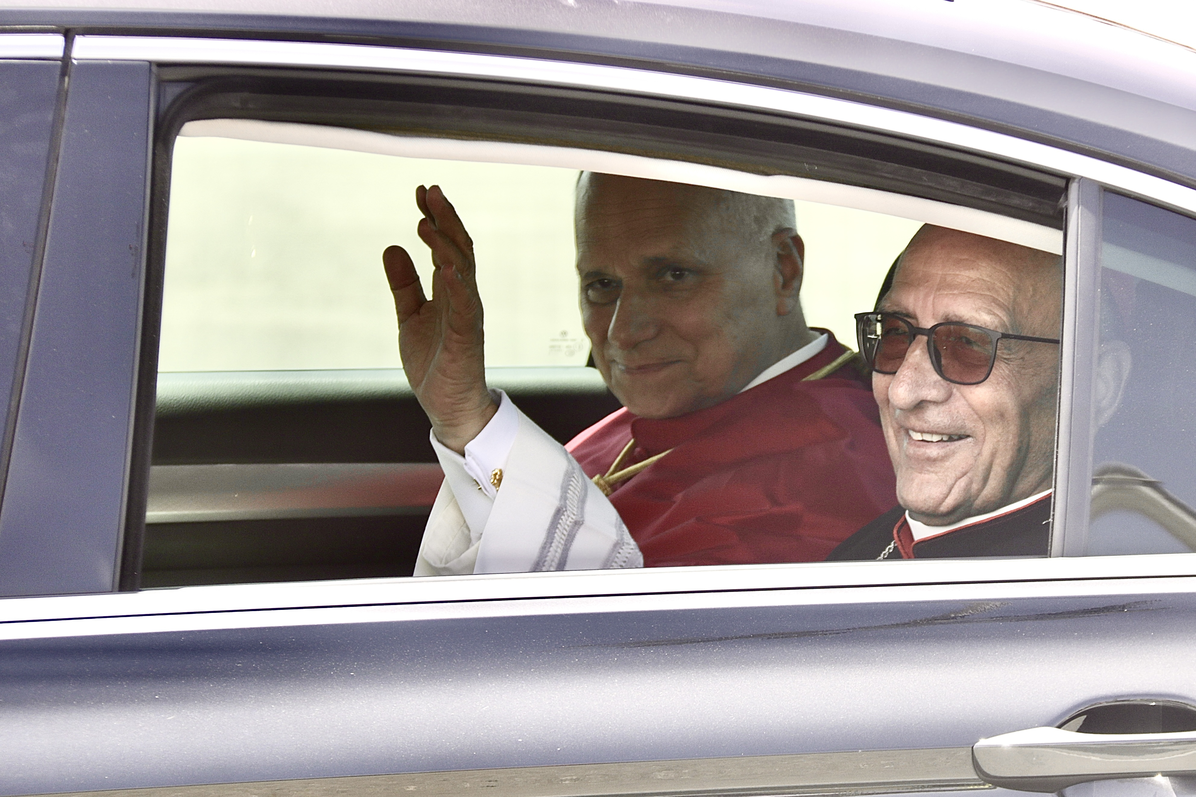 El papa Lleó XIV saluda des del cotxe oficial poc després d'aterrar a l'aeroport del Prat.