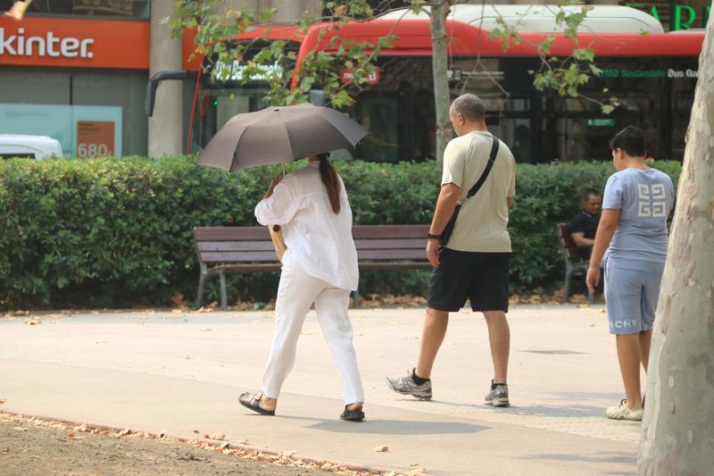 A woman protects herself from the sun with an umbrella during the peak of the heatwave in Barcelona