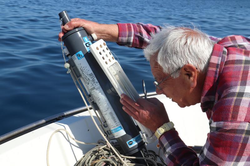 A meteorologist checking the water temperature with a mercury thermometer