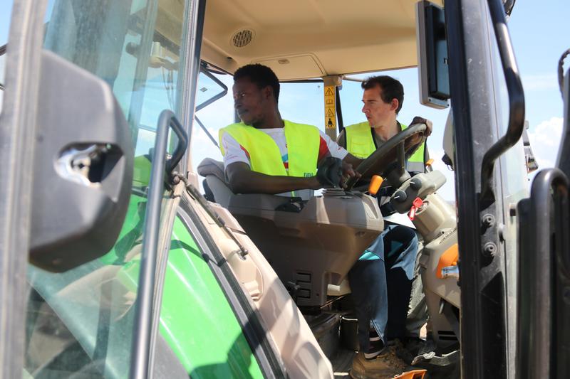 A young student accompanied by his teacher during the moment to turn on the engine of a tractor in the western municipality of Borges Blanques