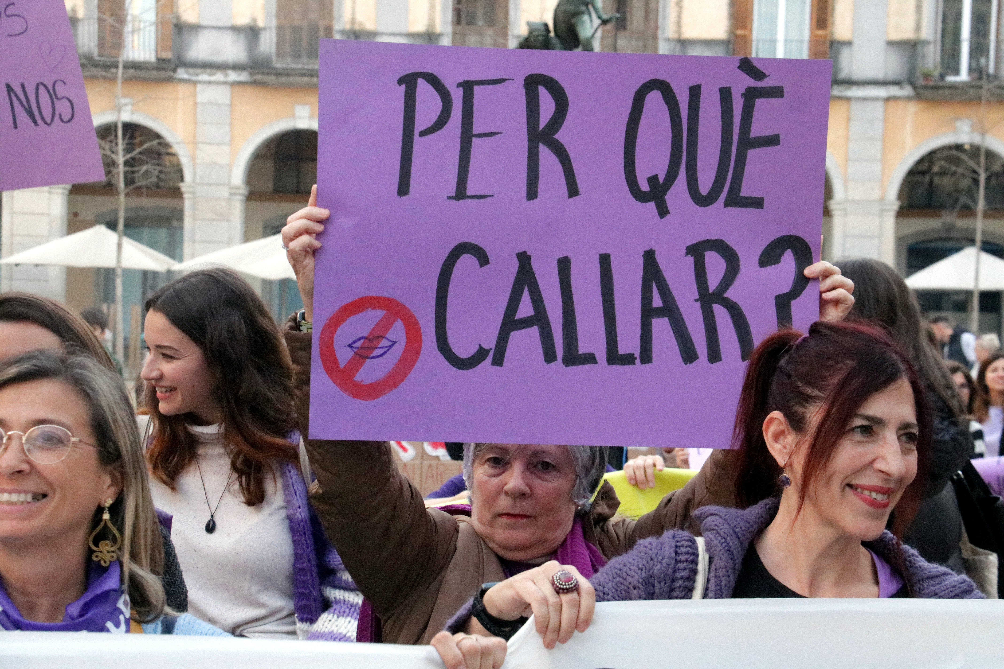 Some women in Girona with a poster reading 'Why staying silent?'