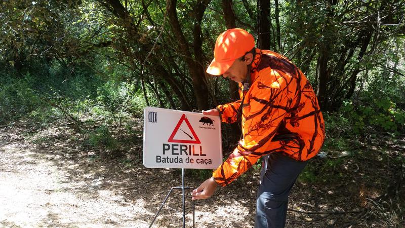 A hunter setting a sign warning of a hunt in Collserola mountains