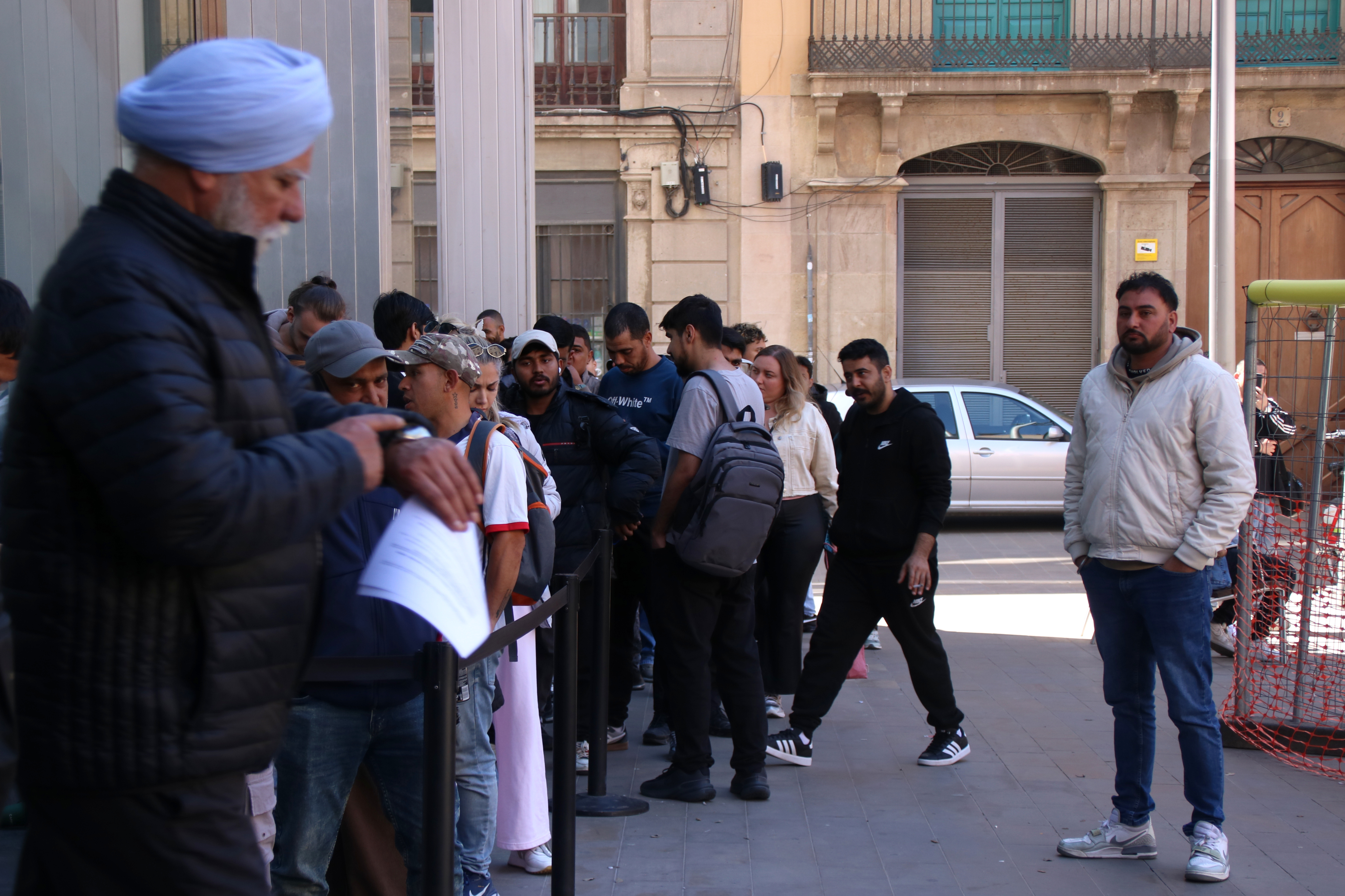 A man looks at his watch while waiting in line for the Citizen's Service Office (OAC) in Plaça Sant Miquel in Barcelona