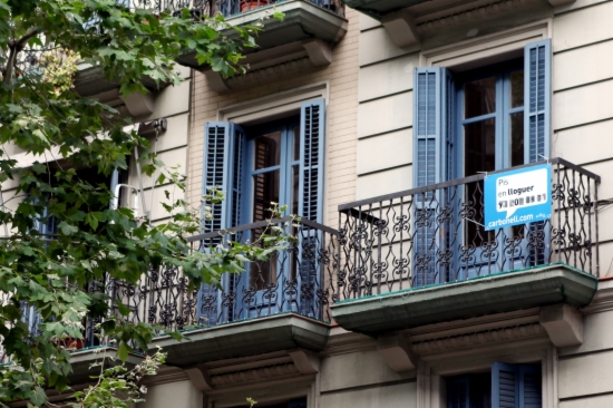 A flat in Barcelona with a 'Lloguer' rental poster hanging from the balcony