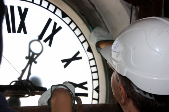 A technician works on the clock of the Plaça de la Vila in Vilanova i la Geltrú