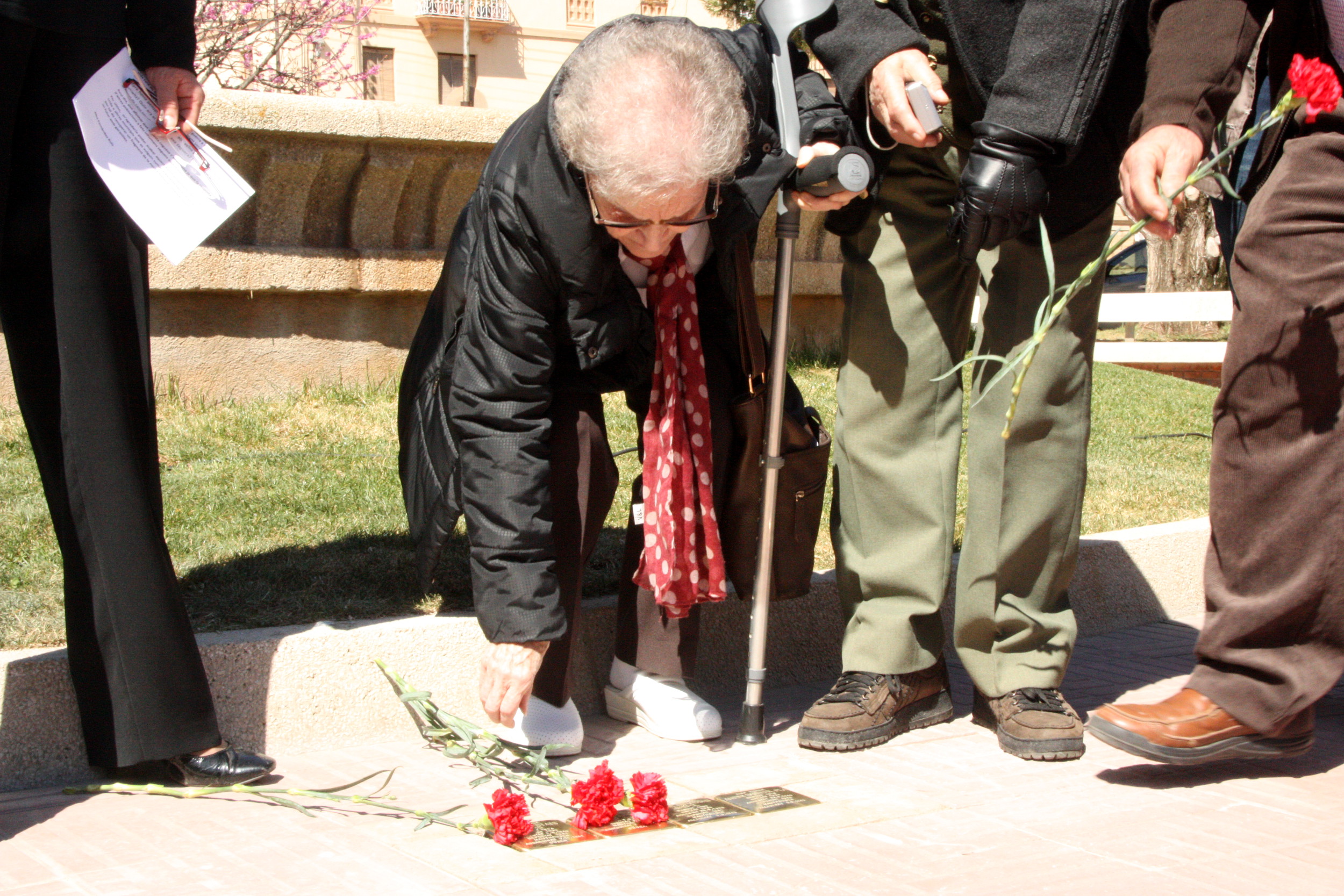 A family member of a victim places a flower by the Stolpersteine in Navàs, in 2015